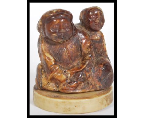 A 19th Century Japanese Meiji period carved lacquered / stained ivory netsuke depicting two figures. Raised on socle base. Me