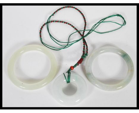 A group of Chinese green jade / green stone jewellery to include necklace pendant of roundel form on string necklace and two 