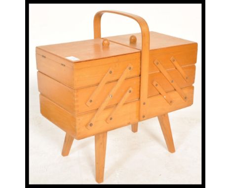 A vintage 20th century retro metamorphic sewing box having metamorphic movements. The fold out sections opening to reveal  st