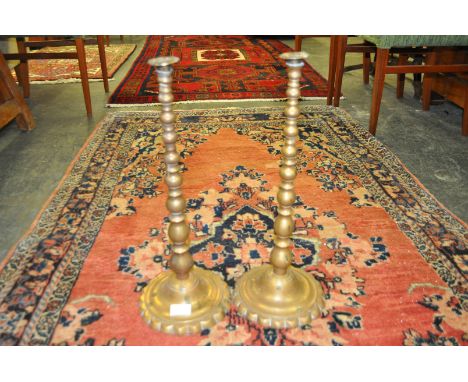 A pair of large 19th Century Victorian brass push candle sticks, raised on a scalloped base having a cast bobbin upright colu