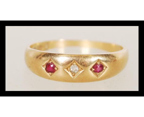 An 18ct gold ruby and diamond ring inset with 2 round cut ruby stones being within star gypsy setting, the central diamond of