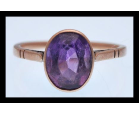 A 9ct gold ring set with a large oval faceted purple stone. Size 2.7g. Weight 2.6g.&nbsp;