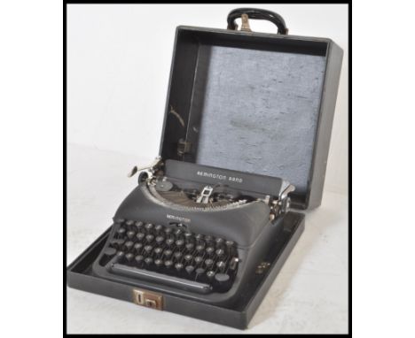 A vintage 20th Century retro Remington Rand typewriter having a matte black finish with white lettering set within a black le