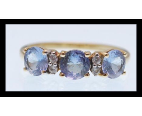 A hallmarked 9ct gold ring prong set with three brilliant cut light blue stones having four white accent stones between. Hall