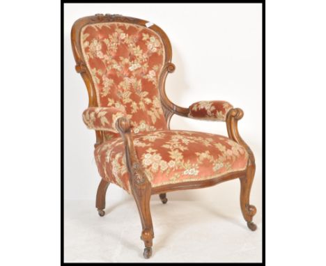 A 19th Century Victorian walnut elbow chair having a spoon back rest with button back upholstery in red with floral sprays, r