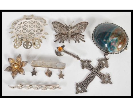 A collection of silver brooches to include one in the from of an axe with a orange stone to the top, a butterfly with filigre