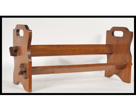 A 1920's oak book trough stand having pierced twin handles sides, angled trough / book rest to centre. 25cm high 53cm wide.&n
