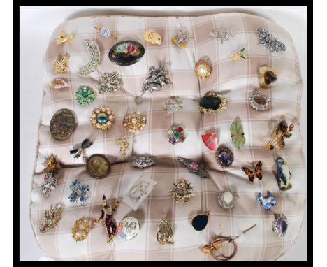 A collection of vintage and retro 20th Century brooches applied to a cushion, to include dress brooches, bug brooches, animal