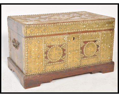 A 19th Century Zanzibar brass studded and armorial decorated trunk chest having large brass panel decorations with brass drop