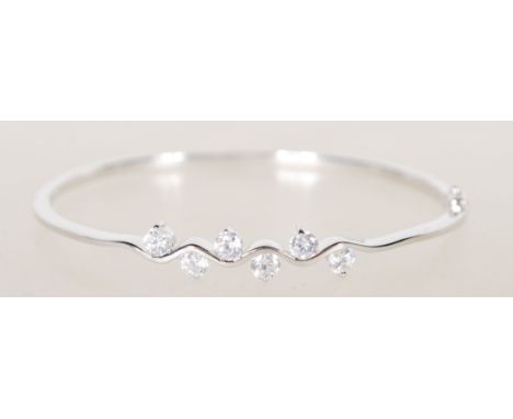 A sterling silver bangle bracelet having six claw set CZ white stones with hidden clasp to side. Weighs 9 grams.