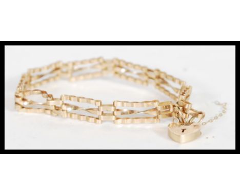 A hallmarked 9ct gold spacer bracelet with a heart lock and safety chain (AF). Hallmarked London 1988. Weight 4.7g. 17cm long