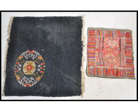 A early 20th Century rug / floor matt having a navy ground with a green and red medallion to one corner along with a ethnic s
