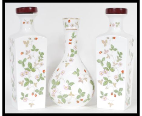 A garniture set of three 20th Century Wedgwood ceramic decanters in the 'Wild Strawberry' pattern, having a white ground with