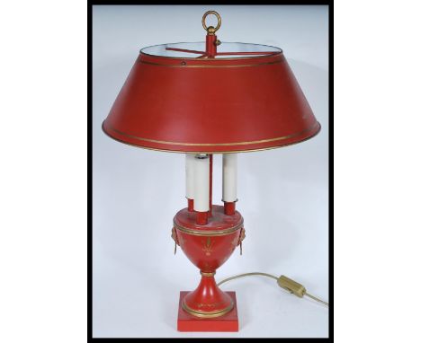 A Louis XVI Bouillotte three light candelabra coaching lamp on a round base with a terracotta coloured shade, raised on a cen