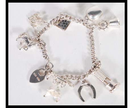 A sterling&nbsp;silver charm bracelet consisting of eight&nbsp;various charmes, to include a house and a miners lamp both of 