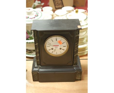 A late Victorian black slate mantel clock having an enamel dial with Roman numerals and eight day movement