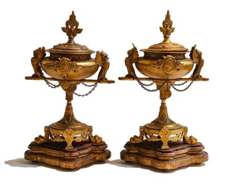 A pair of French gilt metal Classical style urns, 19th century, surmounted by griffin handles and raised on paw feet over qua