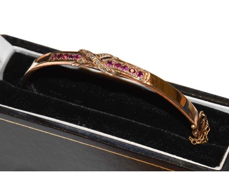 A synthetic ruby and diamond hinged bangle, stamped '9CT', inner measurements 6.0cm by 5.3cmCondition report: Gross weight 19