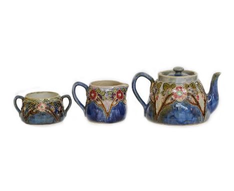 Royal Doulton stoneware, three piece tea service, tube lined with flowers and a mottled blue ground