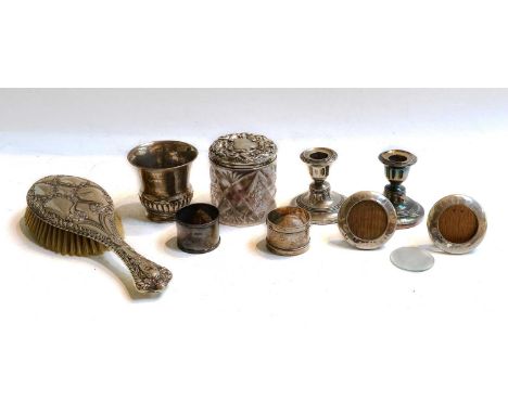 A quantity of silver items, including a pair of dwarf candlesticks, a small beaker brush and serviette rings, together with a