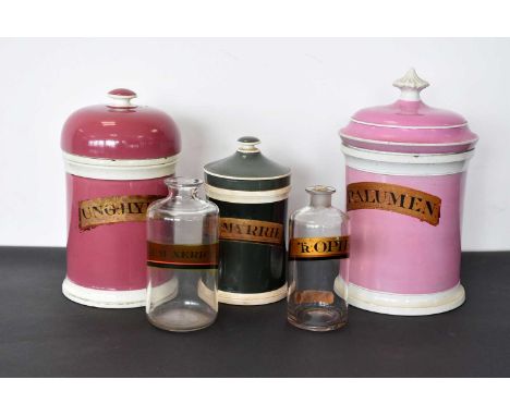 Three ceramic Pharmaceutical lidded containers, two pink, one green, together with two glass examples, all with similar label