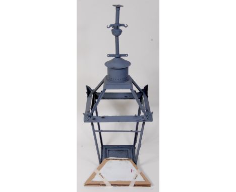 A railway station hanging lamp, in need of restoration, finished in grey primer with areas of corrosion, the lamp is supplied