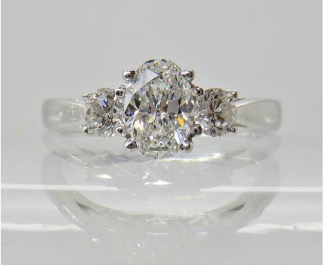 A platinum three stone diamond ring, the central oval cut diamond is estimated approx 0.55cts and flanked by two 0.10cts taki