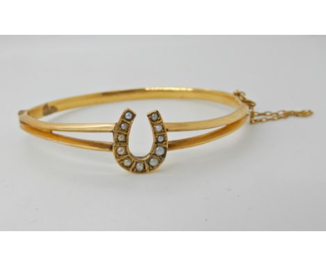 A yellow metal pearl set horseshoe bangle, inner diameter 6cm x 5.4cm, weight 8.3gms Condition Report: Available upon request