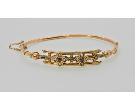 A 9ct gold red gem and pearl bangle, inner diameter 6.5cm, weight 6.2gms Condition Report: Has been mended with lead on one s
