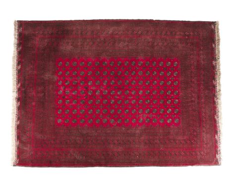 A LARGE AFGHAN RED GROUND WOOL CARPET, the rectangular field filled with a repeating geometric motif enclosed by multiple out