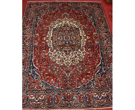 A Persian woollen Bakhtiari carpet, the red ground having a central medallion issuing stylised flowers and foliage, within tr