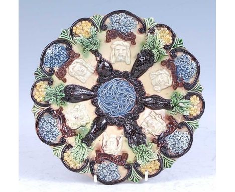A circa 1890 Edward Bingham of Castle Hedingham pottery dish, decorated with applied masks and flora, 26cm diameter