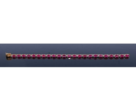 A yellow metal, ruby and white stone tennis bracelet, comprising 23 oval faceted rubies alternating with twenty-three 2mm rou