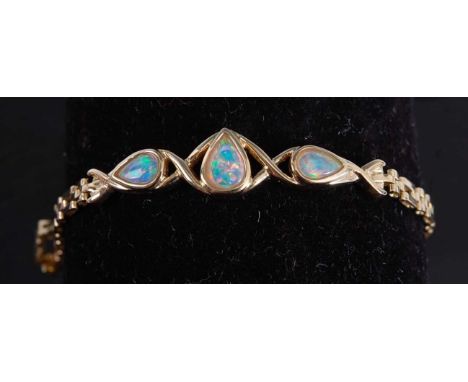 A yellow metal opal bracelet, comprising three pear shaped opal cabochons within a central openwork section, fitted to a two-