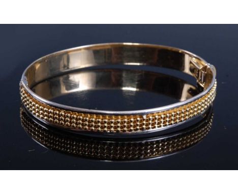 A yellow and white metal hinged hollow oval bangle, with textured bead detail, box clasp with figure of eight catch, bangle w