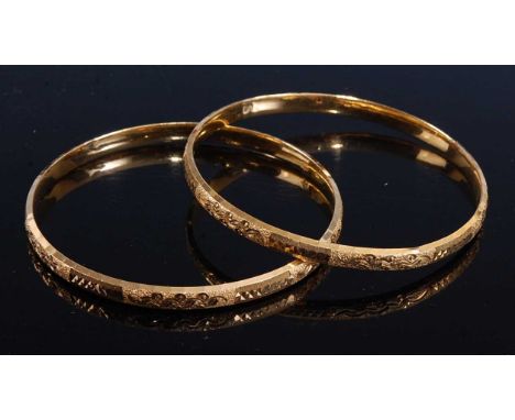 A pair of yellow metal oval bangles, each engraved with a scrollwork and diamond cut pattern, bangle width approx 5mm, inner 
