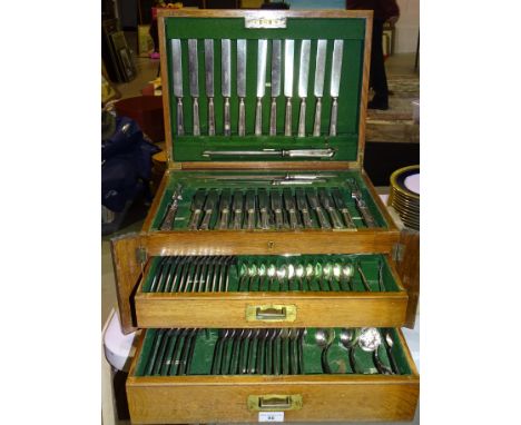 A near complete canteen of Elkington silver-plated cutlery contained in an oak two-drawer fitted cabinet. 