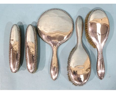 A five-piece silver-backed dressing table set, comprising two clothes brushes, two hair brushes and a hand mirror, Birmingham