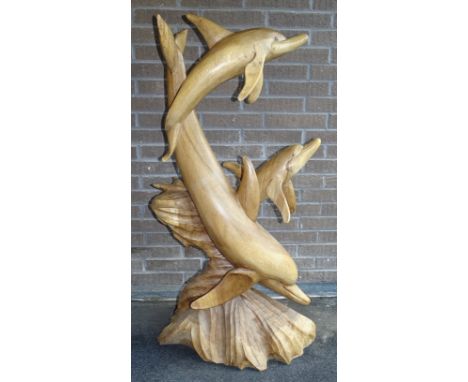 A carved wood sculpture of three dolphins, mother with two young, on naturalistic base, carved from a single trunk, 130cm hig