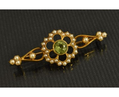An Edwardian peridot and seed pearl brooch, central round cut peridot, within six petal open surround encrusted with seed pea