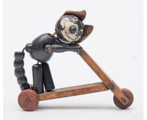 An early 20th century wooden Felix the Cat articulated figure riding a scooter,: with 'Felix' stencilled across the body, (fe