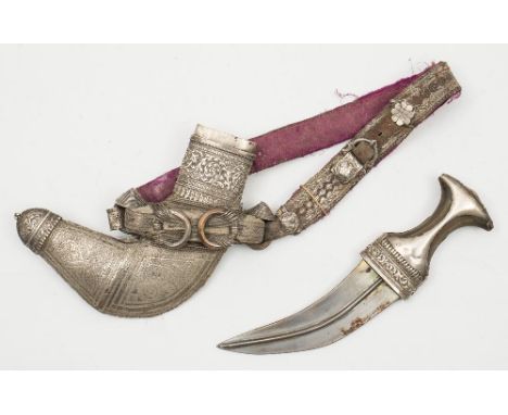 A 19th century Arabic jambiya:, the short curved blade with central strengthening rib over a white metal mounted horn handle,