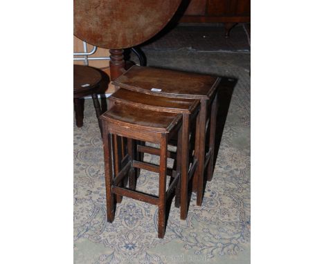 A 1940's Oak Nest of three bow fronted Occasional Tables with moulded tops, standing on square legs with surround stretchers.