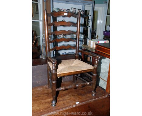 A 19th c. style ladder back Elbow Chair with five shaped bars to the back in turned supports, shaped arms and rush seat, stan