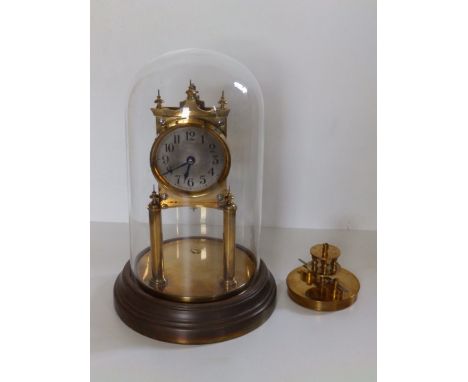 A brass mantel clock under glass dome.