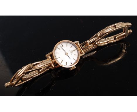 A lady's 9ct yellow gold Omega manual wind wristwatch, the round cream baton dial fitted to a later 9ct gold and spring metal