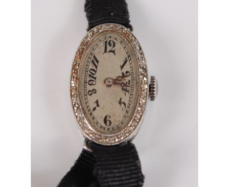 An Art Deco platinum manual wind cocktail watch, having an oval silver Arabic dial and bezel grain set with 37 single cut dia