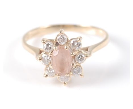 An 18ct yellow gold, pink topaz and diamond oval cluster ring, featuring a centre oval pink topaz within a border of eight ro