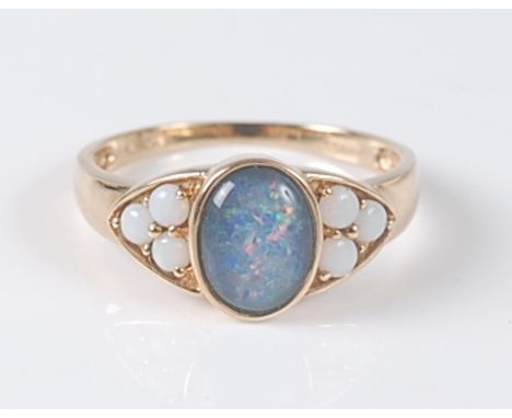 A 9ct yellow opal triplet dress ring, the opal triplet cabochon measuring approx 9 x 6.7 x 3mm, in a bezel setting, with a tr