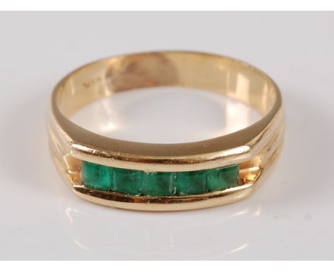 A yellow metal half hoop eternity ring, comprising five square cut Columbian emeralds in a channel setting, emerald dimension